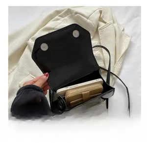 Detail view of small patent leather crocodile bag showing capacity for phone and wallet