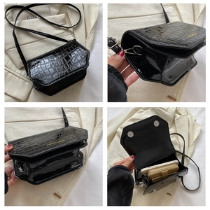 Detail of black faux crocodile patent leather bag showing texture and magnetic clasp