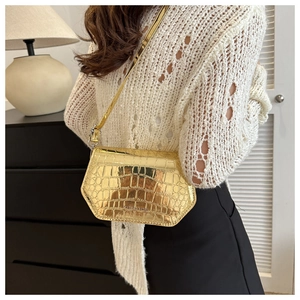Close-up of golden crocodile pattern square bag with metallic finish and flap detail