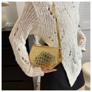 Golden crocodile embossed mini crossbody bag shown with a white open-knit sweater