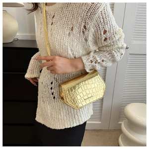 Detail view of mini gold crossbody bag with crocodile pattern texture on patent leather