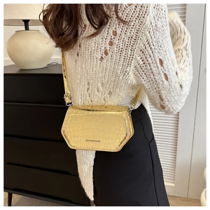 Detail view of a gold crocodile pattern leather crossbody bag with metallic finish