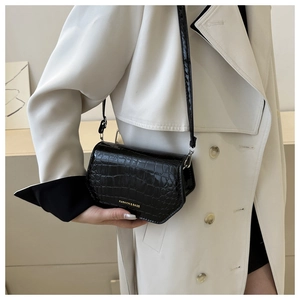 Detail of black crocodile pattern leather crossbody bag with gold fashion lettering