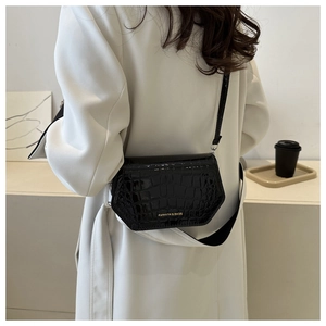 Detail of black crocodile embossed hexagonal crossbody bag with fashion text and leather strap