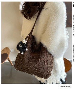 Détail du sac cabas marron foncé avec texture matelassée et breloque peluche en bandoulière