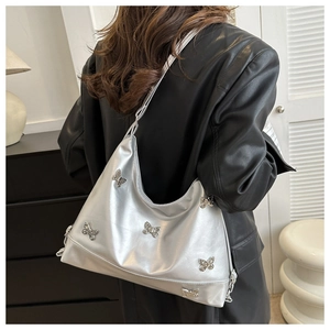 Sac bandoulière argenté métallisé orné de papillons porté par un mannequin de profil