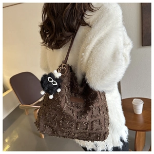 Détail du sac fourre-tout marron texturé avec breloque peluche dans un cadre de café