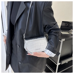Detail of silver crocodile pattern crossbody bag showing texture and metal ring