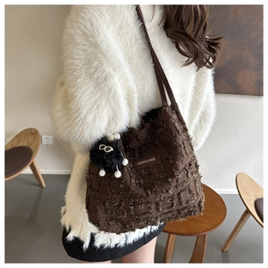 Détail d'un sac cabas marron en peluche avec pompon et texture textile douce