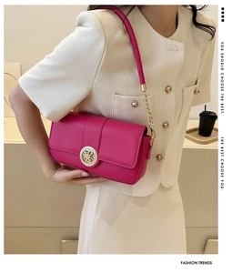 Close-up of pink leather handbag with gold chain detail and circular metal buckle