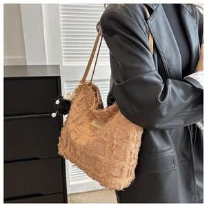 Grand sac cabas marron à franges avec pompon décoratif porté par le mannequin