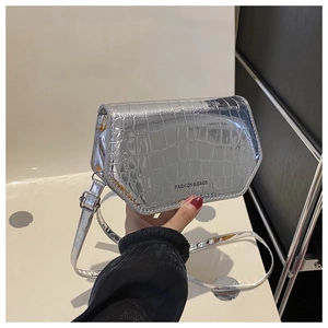 Detail of silver crocodile pattern crossbody bag with metal mirror finish and logo