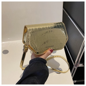 Detail of gold patent faux leather crossbody bag featuring fine crocodile pattern texture