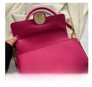 Detail of rose red leather shoulder bag showing the golden magnetic snap and interior flap