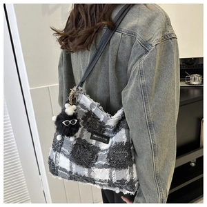 Gros plan sur un sac seau en tweed noir et blanc avec franges et breloque monstre