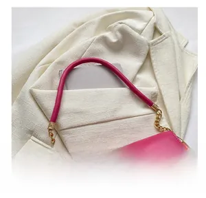 Detail of rose red leather crossbody bag featuring circular metal hardware and chain strap