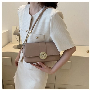 Detail of tan leather shoulder bag with gold hollow buckle and metal chain strap