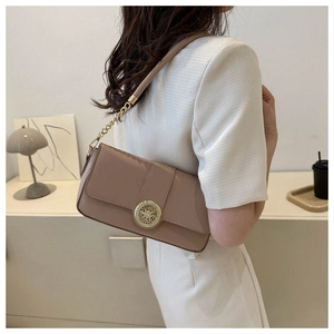 Detailed view of the vintage gold circular buckle on a Morandi tone shoulder bag