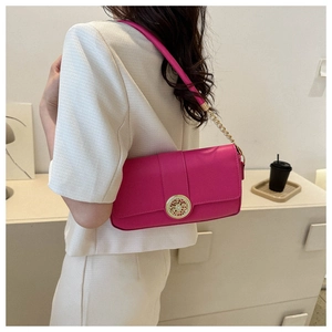 Detail of magenta baguette bag featuring gold decorative buckle and chain strap