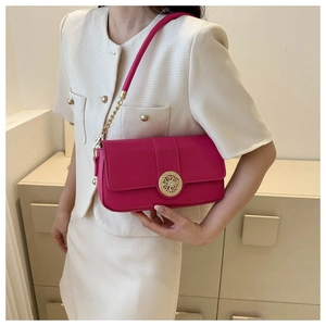 Rose pink shoulder bag with gold hollow clasp worn over a stylish beige tweed suit