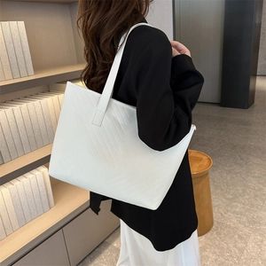 Minimalist white tote bag with V-shaped quilting and long shoulder straps for daily commute