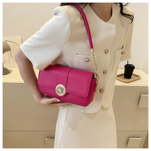 Detail of hot pink leather crossbody bag featuring an ornate gold buckle and chain strap