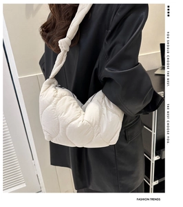 Detail of white quilted cloud bag featuring smooth satin finish and wide knotted strap