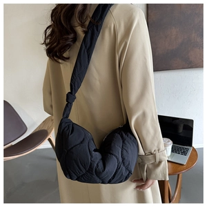 Close-up of black quilted cloud bag with knotted shoulder strap detail on a female model