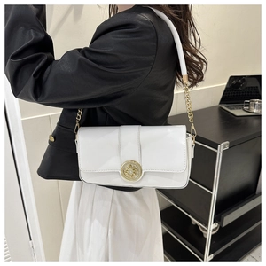 Detail of white chain bag with round gold buckle on a model wearing black blazer