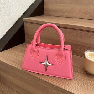 Sac à main rose en cuir avec emblème étoile argenté sur un escalier en bois