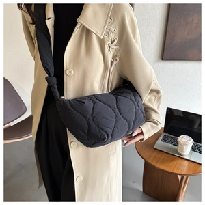 Scatto lifestyle della borsa a tracolla trapuntata nera indossata con un trench beige