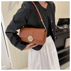 Detail of brown leather shoulder bag with gold hollow circular metal buckle and chain strap