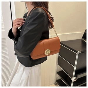 Detail of vintage brown leather underarm bag with gold metal buckle and chain strap