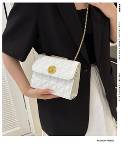 Détail du sac à chaîne en cuir matelassé blanc avec boucle dorée en cristal sur modèle