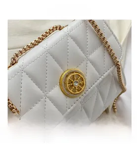 Gros plan sur un sac blanc matelassé avec une boucle dorée ornée de strass brillants