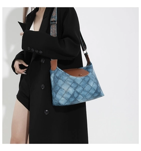 Detail der Denim-Tragetasche mit brauner Lederklappe und gewebtem Ethno-Schultergurt