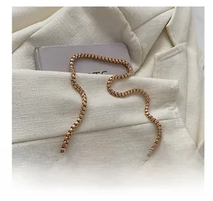 Détail d'une bandoulière chaîne dorée sur un sac à main blanc matelassé pour femme