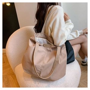Detail of khaki nylon tote bag with leather logo patch and wide shoulder strap
