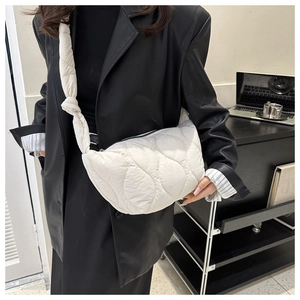 Dettaglio borsa a mezza luna trapuntata bianca con tracolla annodata e blazer nero