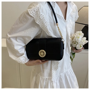 Detail of elegant black crossbody bag with vintage gold clasp and chain strap on a model