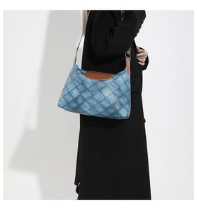Detail der gesteppten Vintage-Jeans-Tasche mit Lederbesatz an einem schwarzen Mantel