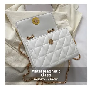 Gros plan du fermoir magnétique doré sur le petit sac à bandoulière matelassé blanc
