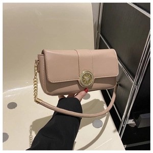 Close-up of beige leather crossbody bag featuring an ornate gold buckle and rhinestone detail
