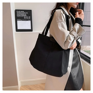 Minimalist large black canvas tote bag shown on shoulder for daily casual commute use