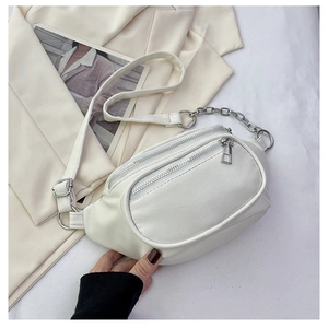 Dettaglio borsa a tracolla bianca con zip argento e catena metallica su blazer beige chiaro