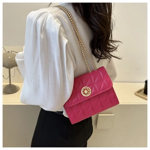 Sac bandoulière matelassé magenta avec chaîne dorée porté par un mannequin