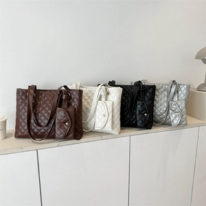 Quilted oversized tote bags set in four colors with matching coin purses on a minimal table