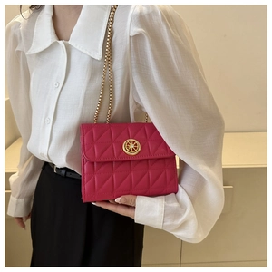 Détail du sac matelassé fuchsia avec bandoulière chaîne dorée et emblème circulaire