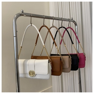 Detail showing five colors of leather flap bags with gold floral clasps on a rack