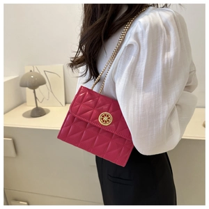 Détail du sac bandoulière matelassé rose rouge avec chaîne dorée et emblème